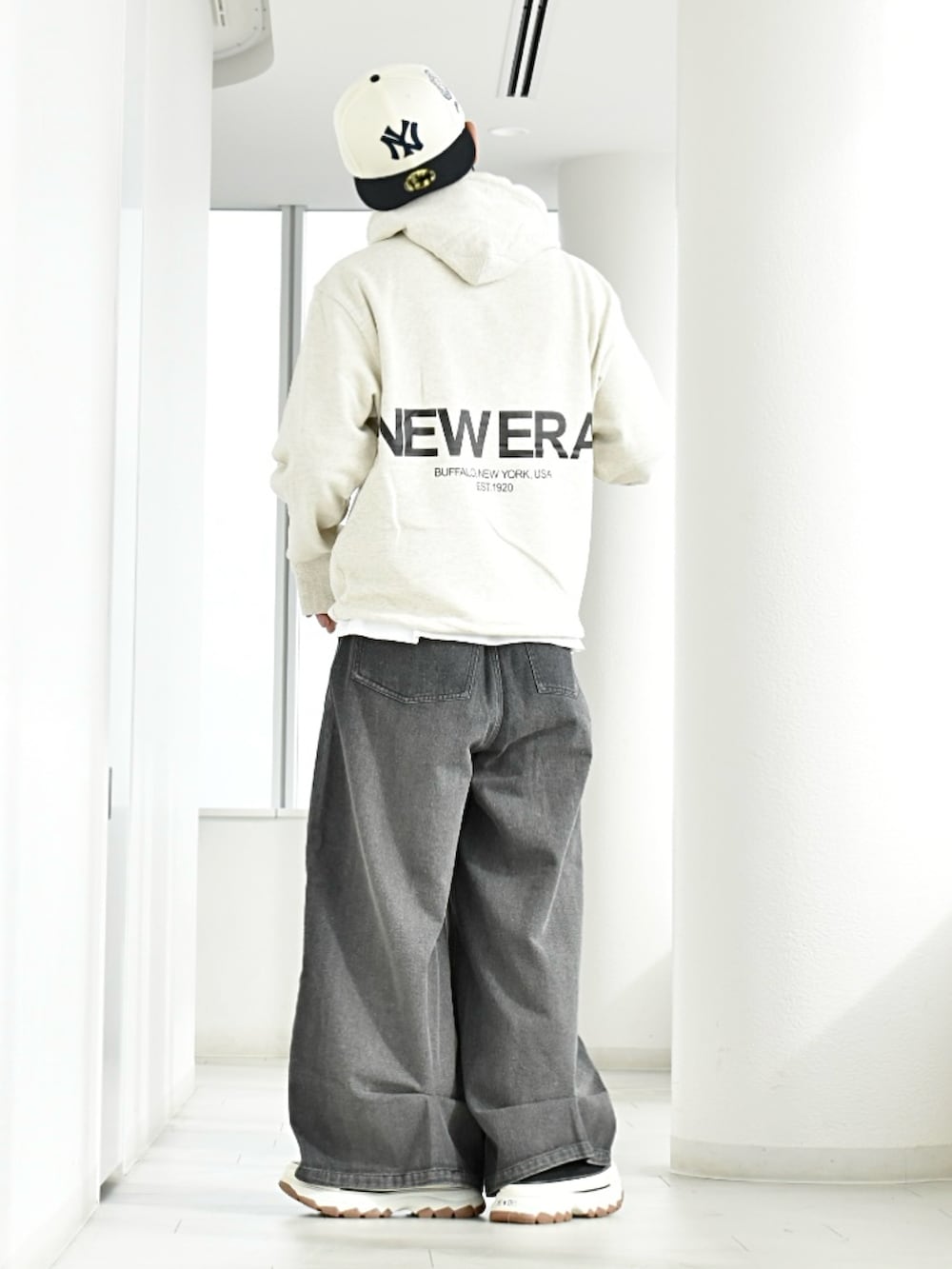 ブラック系のデニムパンツ、ホワイト系のパーカー、ブラック系のスニーカーを着用したメンズの冬コーディネートの2枚目の写真