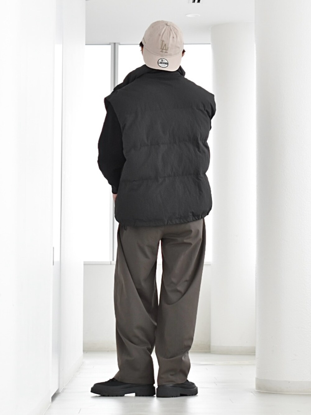 ブラック系のダウンベスト、その他のスラックス、ブラック系のブーツを着用したメンズの秋コーディネートの3枚目の写真