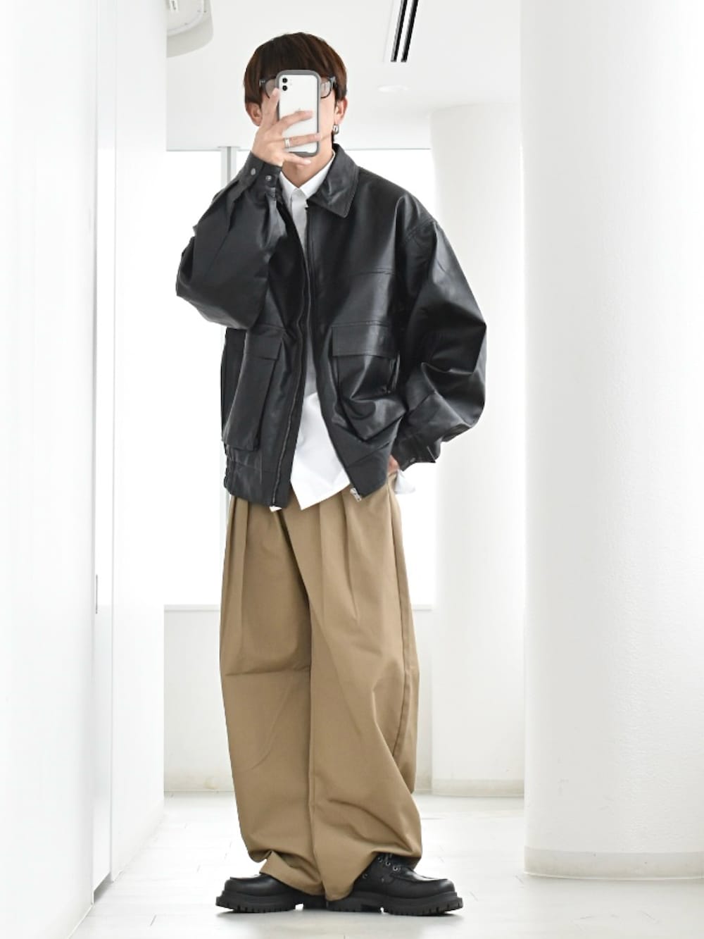 ブラック系のブルゾン、ホワイト系のシャツ/ブラウス、ベージュ系のチノパンツを着用したメンズの春コーディネートの2枚目の写真