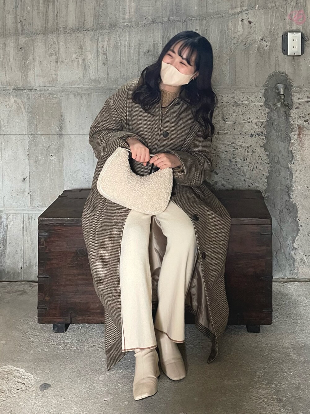 ベージュ系のステンカラーコート、ホワイト系のハンドバッグ、ホワイト系のブーツを着用したレディースの冬コーディネートの2枚目の写真