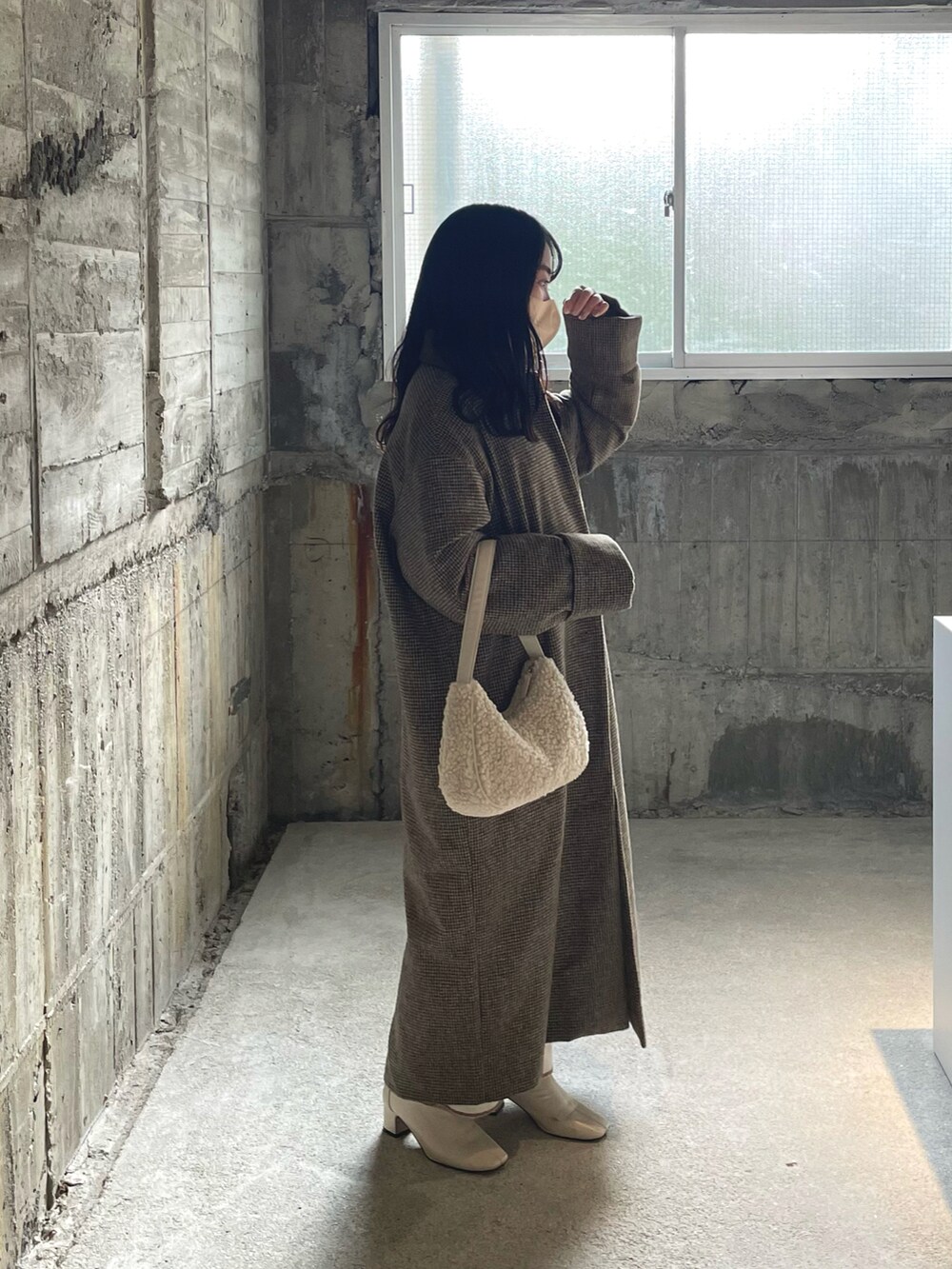 ベージュ系のステンカラーコート、ホワイト系のハンドバッグ、ホワイト系のブーツを着用したレディースの冬コーディネートの3枚目の写真