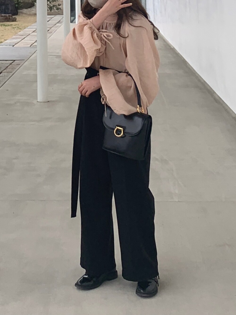 ブラック系のハンドバッグ、ブラック系のパンツ、ブラック系のローファーを着用したレディースの春コーディネートの2枚目の写真