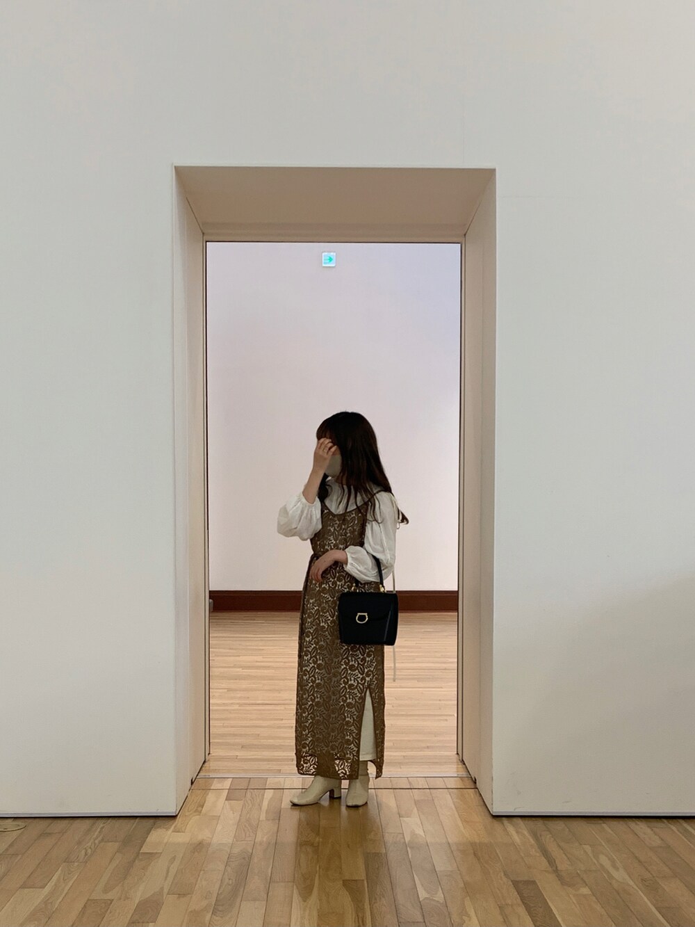 ブラウン系のワンピース、ホワイト系のブーツ、ホワイト系のスカートを着用したレディースの春コーディネートの2枚目の写真