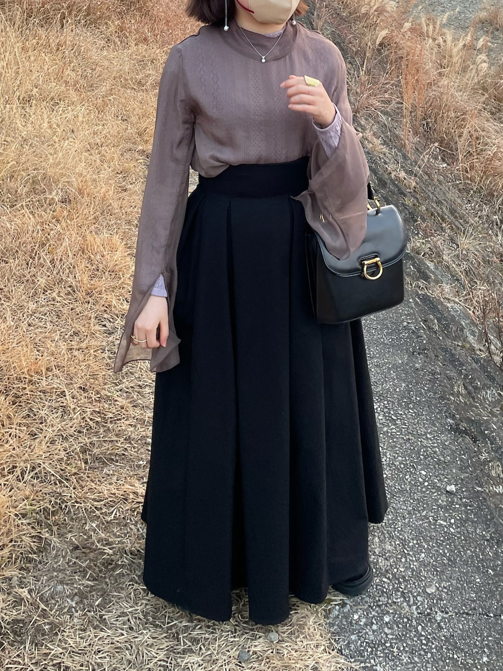 ブラック系のハンドバッグ、ブラック系のスカート、グレー系のその他トップスを着用したレディースの冬コーディネートの3枚目の写真
