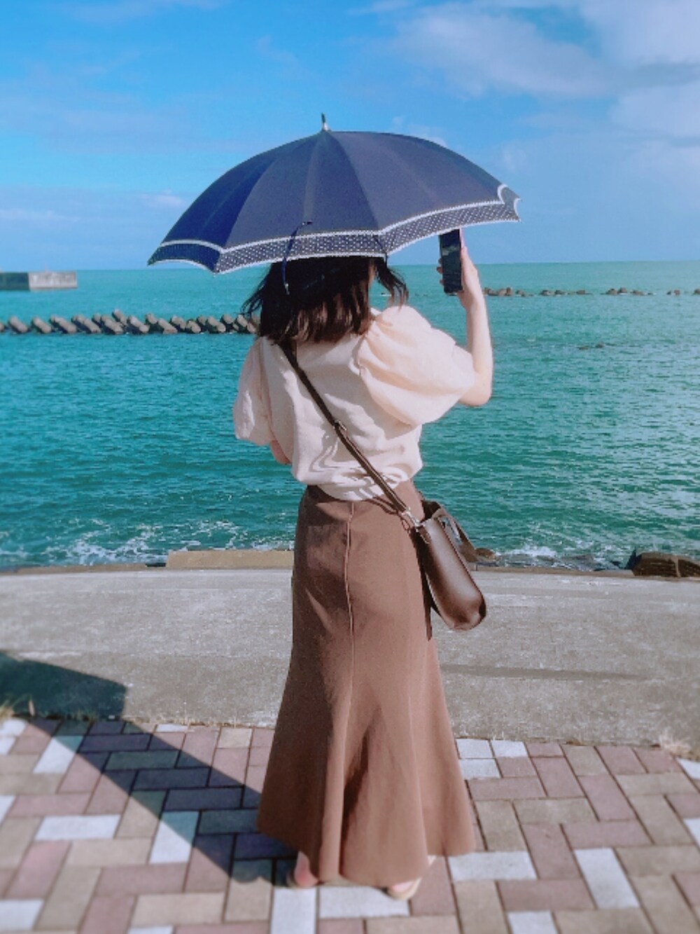 ベージュ系のサンダル、ブラウン系のスカート、ブラウン系のショルダーバッグを着用したレディースの夏コーディネートの2枚目の写真