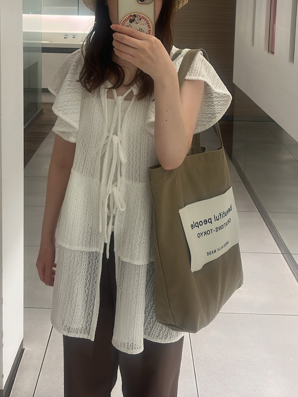 ベージュ系のトートバッグ、ホワイト系のチュニック、ホワイト系のトップスを着用したレディースの夏コーディネートの2枚目の写真