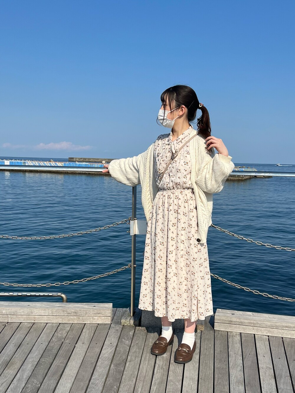 ホワイト系のカーディガン/ボレロ、ベージュ系のショルダーバッグ、ホワイト系のワンピースを着用したレディースの春コーディネートの2枚目の写真