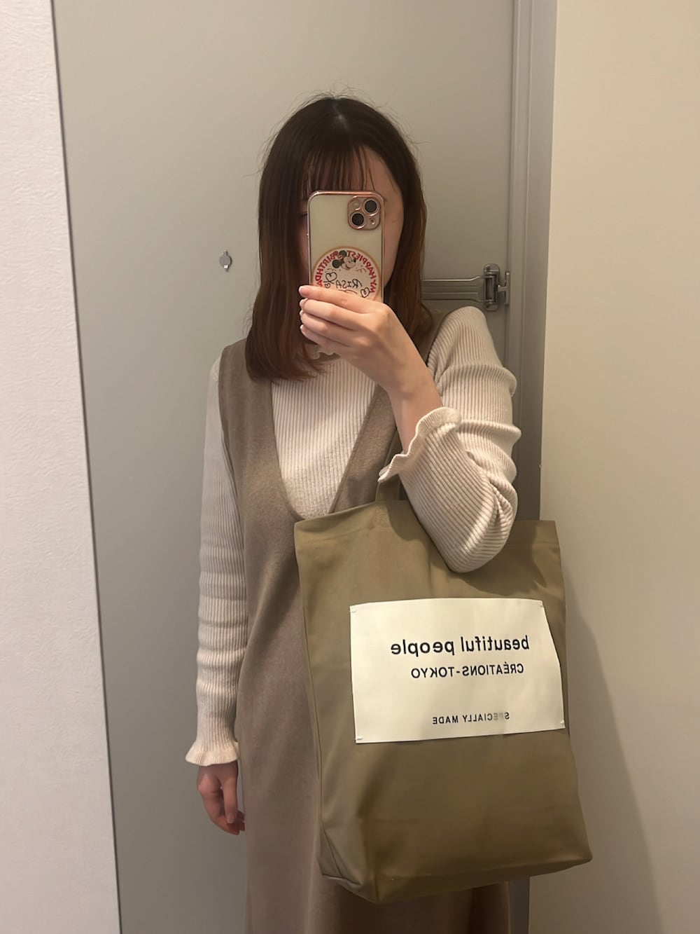 ベージュ系のトートバッグ、ホワイト系のニット/セーター、ブラウン系のワンピースを着用したレディースの秋コーディネートの2枚目の写真