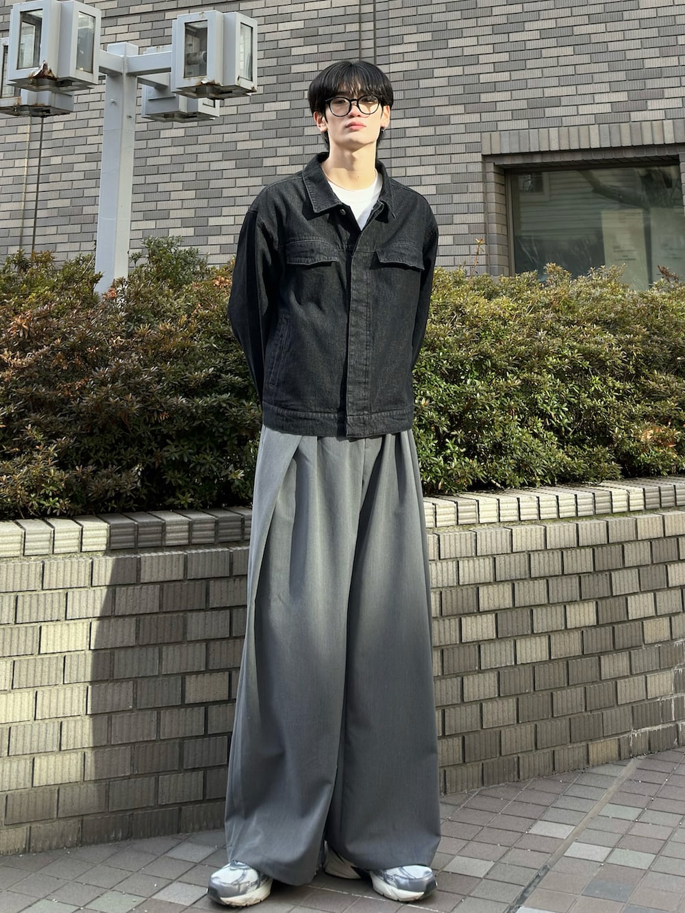 ブラック系のデニムジャケット、グレー系のスラックス、グレー系のスニーカーを着用したメンズの春コーディネートの5枚目の写真