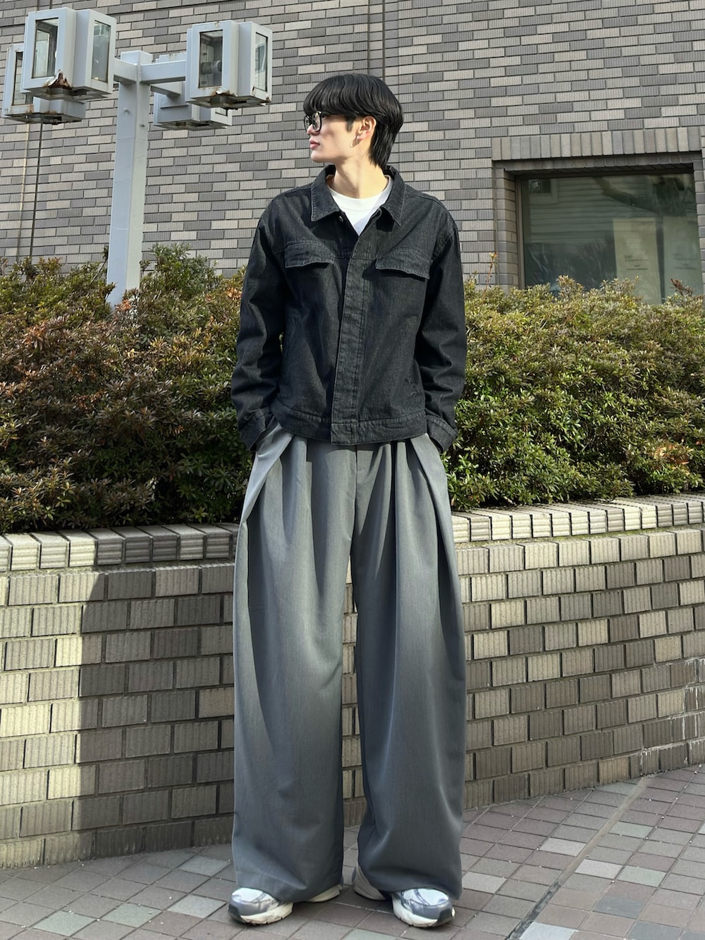 ブラック系のデニムジャケット、グレー系のスラックス、グレー系のスニーカーを着用したメンズの春コーディネートの3枚目の写真