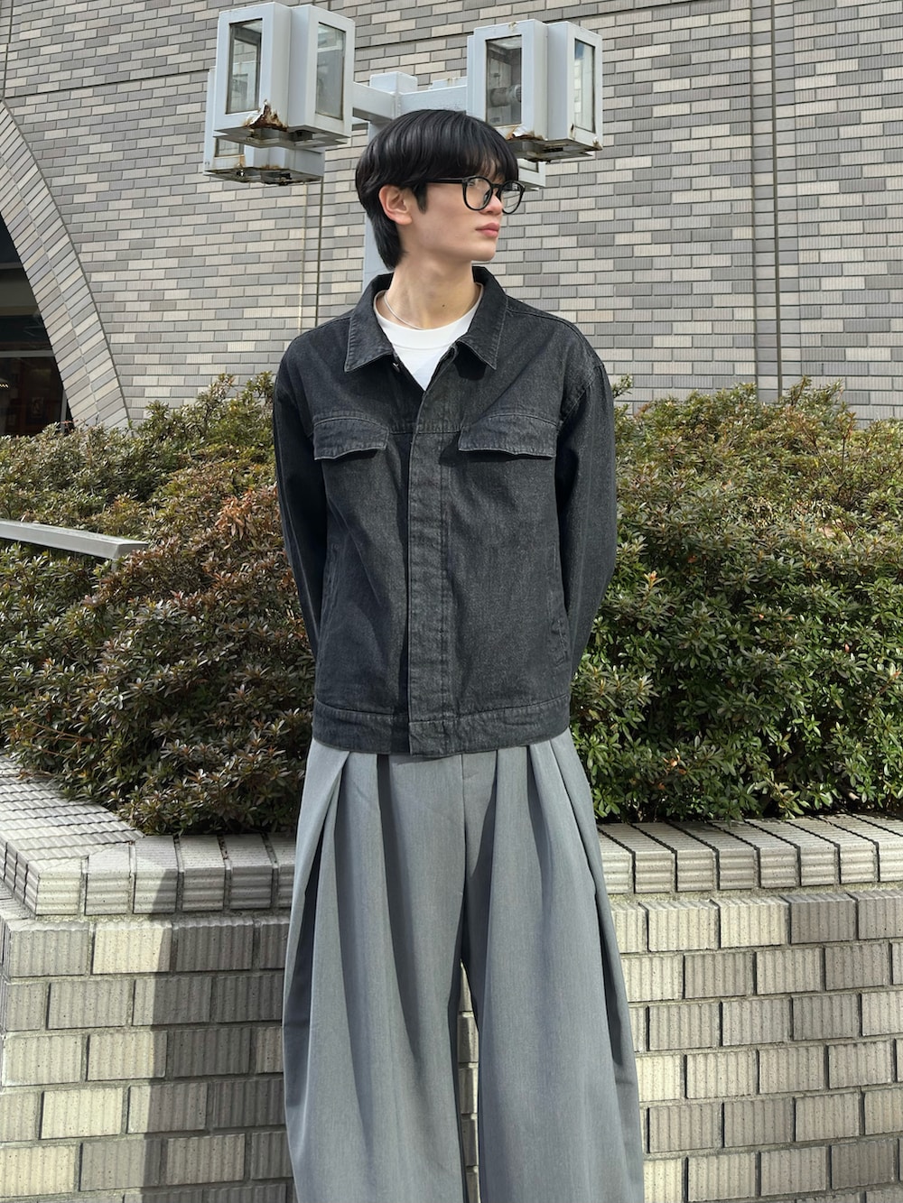 ブラック系のデニムジャケット、グレー系のスラックス、グレー系のスニーカーを着用したメンズの春コーディネートの4枚目の写真