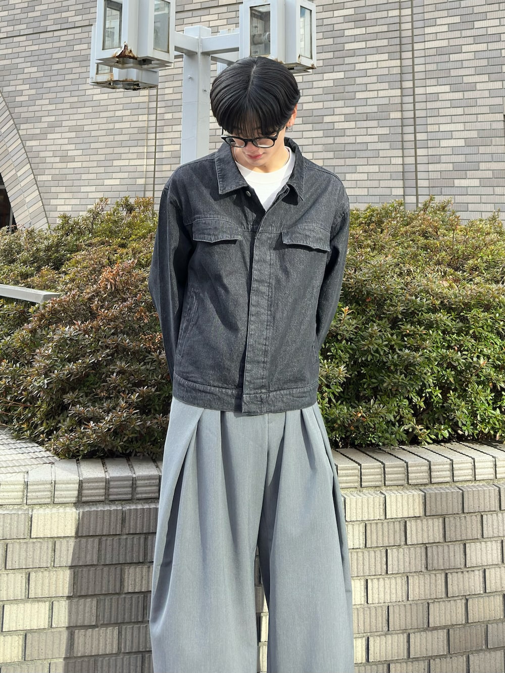 ブラック系のデニムジャケット、グレー系のスラックス、グレー系のスニーカーを着用したメンズの春コーディネートの2枚目の写真