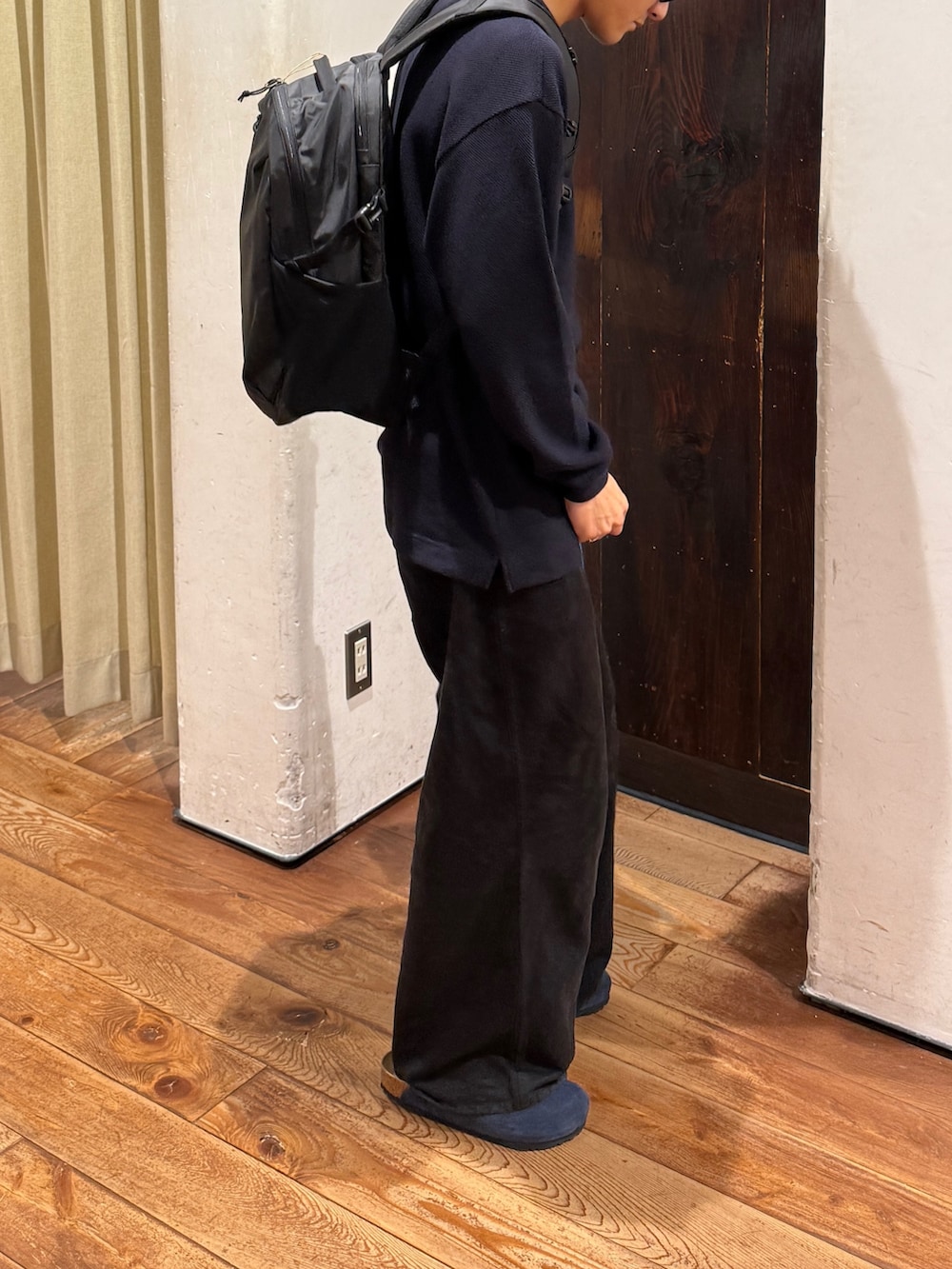 ブラック系のバックパック/リュック、グレー系のTシャツ/カットソー、ブルー系のサンダルを着用したメンズの秋コーディネートの4枚目の写真