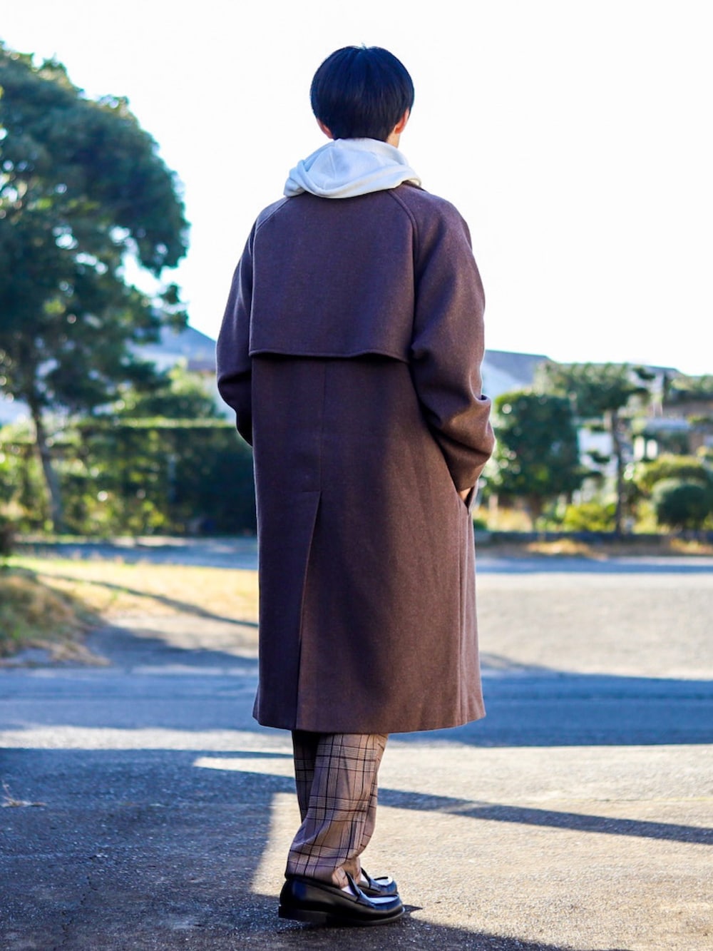 ベージュ系のトレンチコート、ホワイト系のパーカー、ブラウン系のスラックスを着用したメンズの冬コーディネートの3枚目の写真