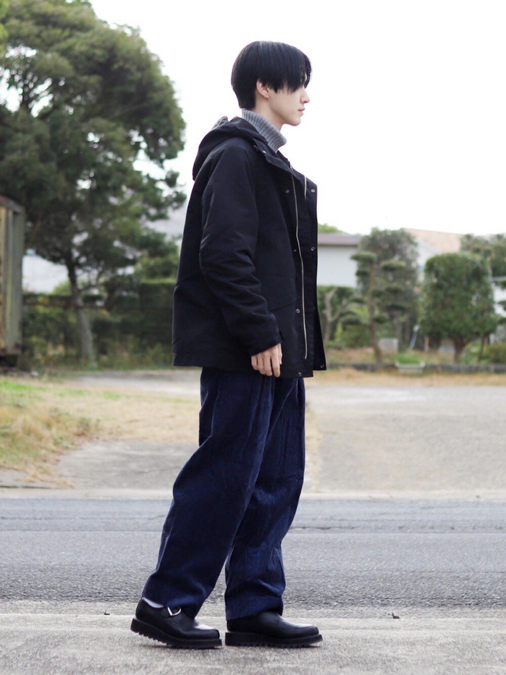 ブラック系のマウンテンパーカー、グレー系のニット/セーター、ブルー系のスラックスを着用したメンズの冬コーディネートの3枚目の写真