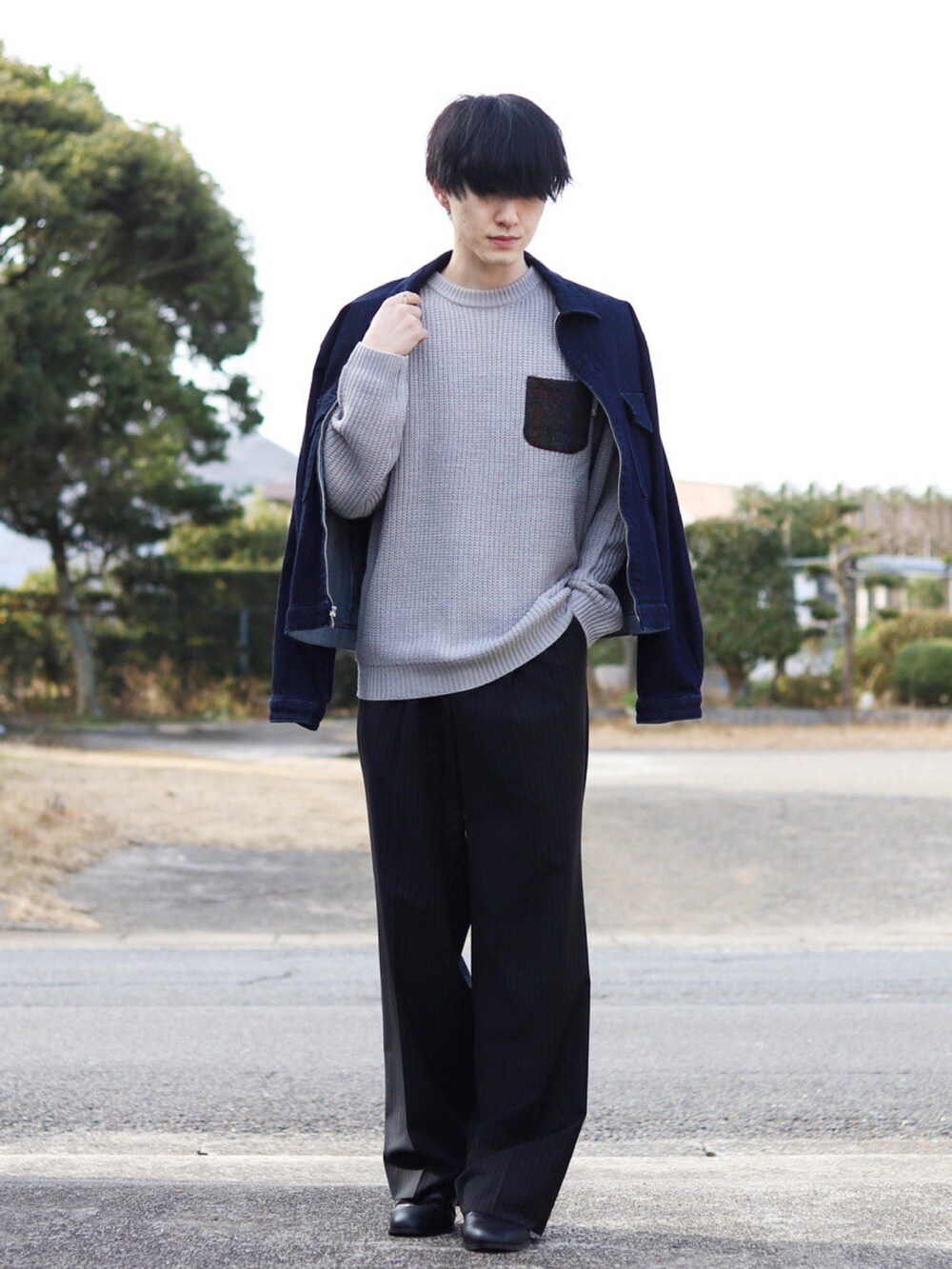 グレー系のニット/セーター、ブルー系のセットアップ、ブラック系のスラックスを着用したメンズの冬コーディネートの2枚目の写真