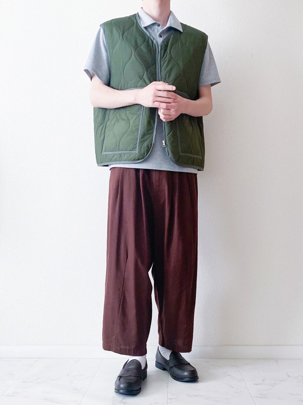 グレー系のポロシャツ、グリーン系のベスト、ブラウン系のその他パンツを着用したメンズの春コーディネートの2枚目の写真