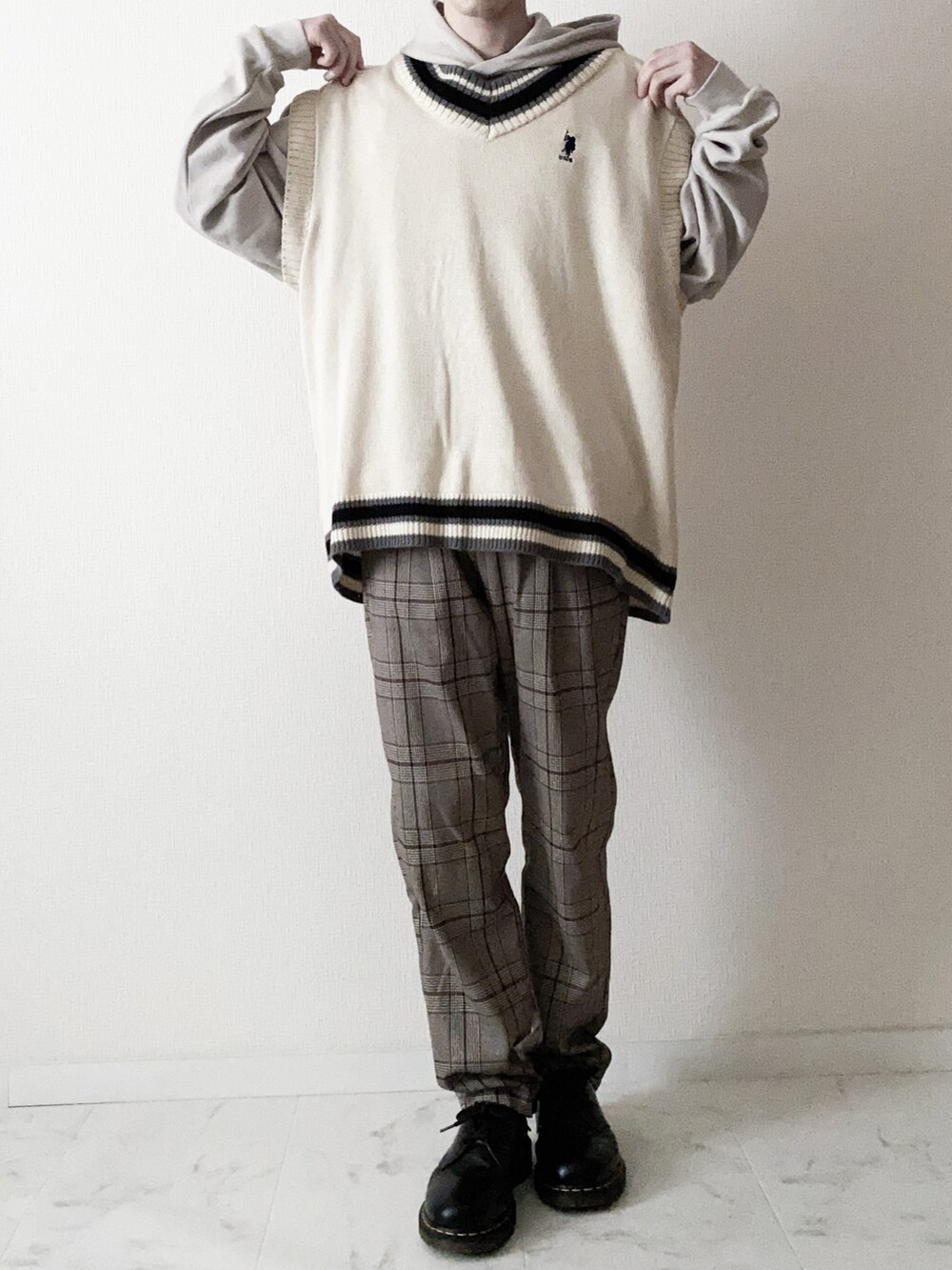 ホワイト系のベスト、ベージュ系のパーカー、ブラウン系のスラックスを着用したメンズの冬コーディネートの2枚目の写真