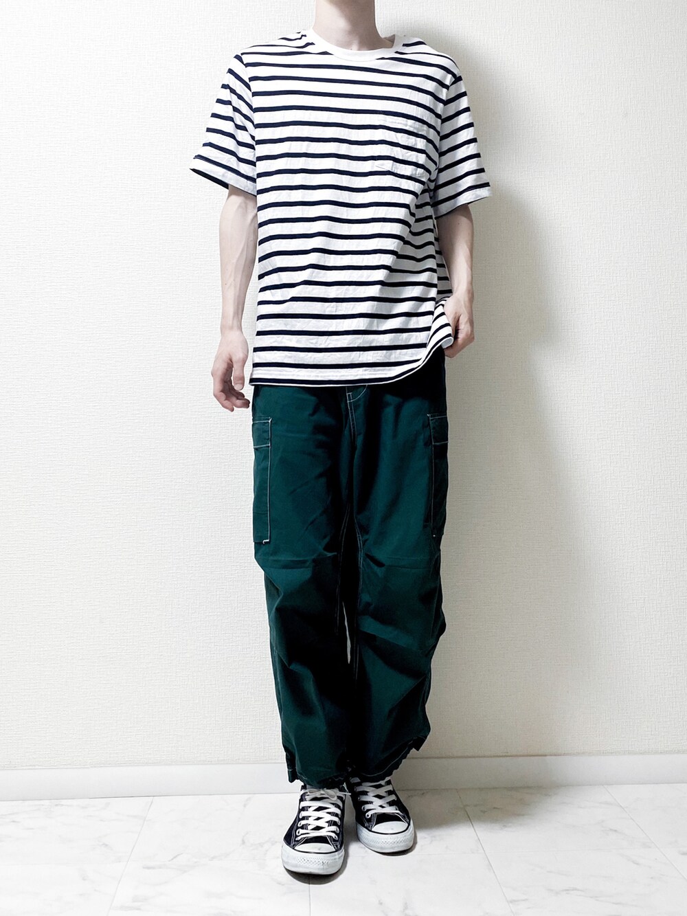 グリーン系のデニムパンツ、ホワイト系のトップス、ブラック系のスニーカーを着用したメンズの春コーディネートの2枚目の写真