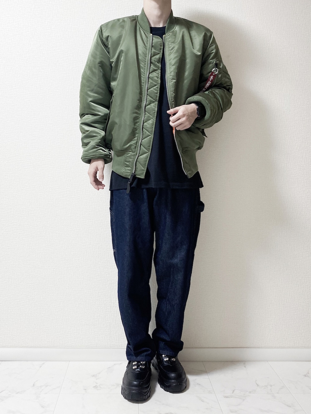 グリーン系のMA-1、ブルー系のデニムパンツ、ブラック系のTシャツ/カットソーを着用したメンズの秋コーディネートの2枚目の写真