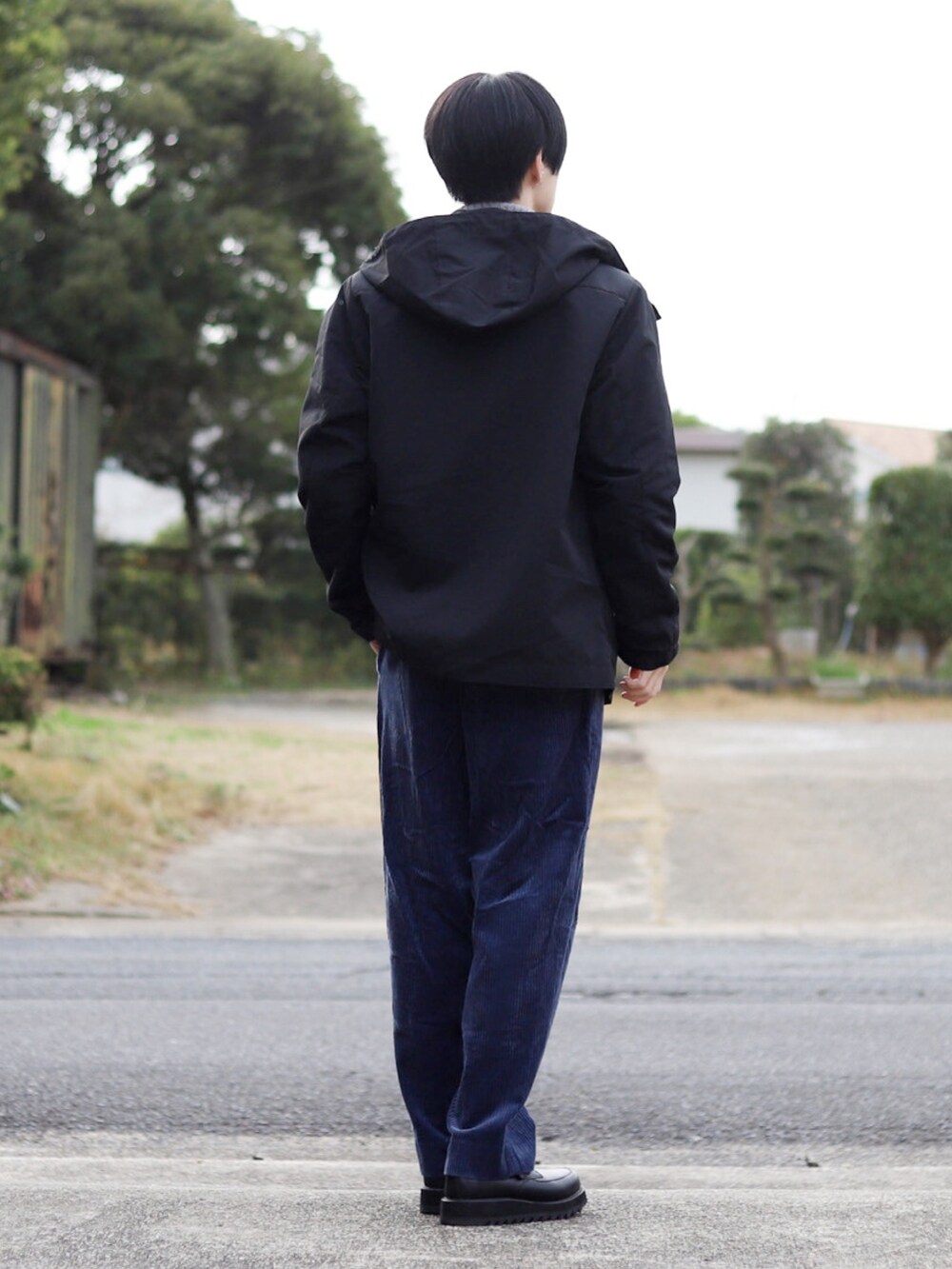 ブラック系のマウンテンパーカー、グレー系のニット/セーター、ブルー系のスラックスを着用したメンズの冬コーディネートの4枚目の写真