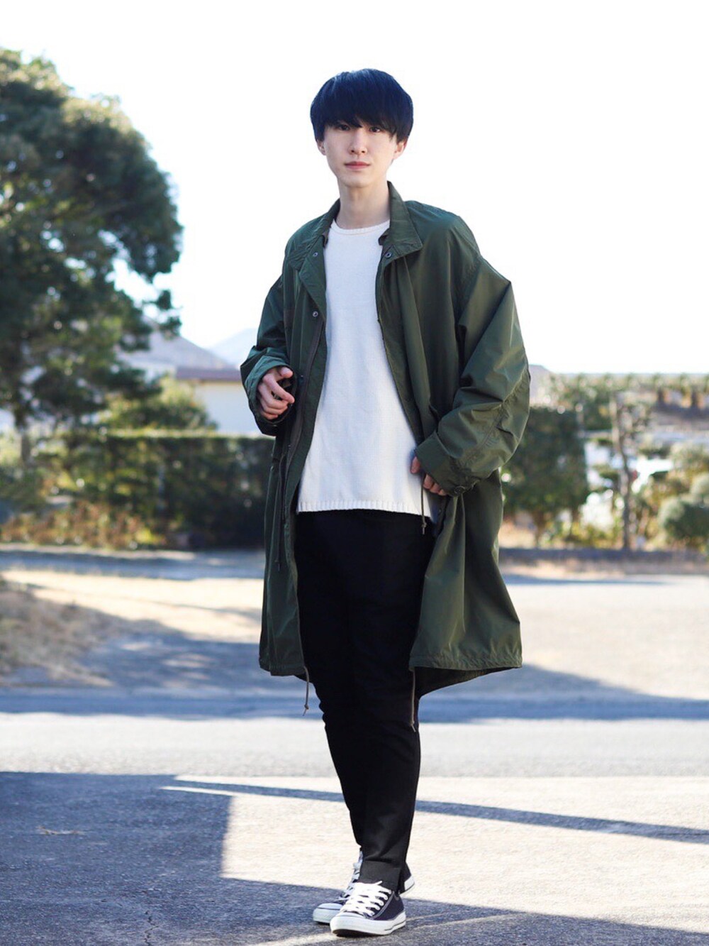 グリーン系のモッズコート、ホワイト系のニット/セーター、ブラック系のデニムパンツを着用したメンズの冬コーディネートの2枚目の写真