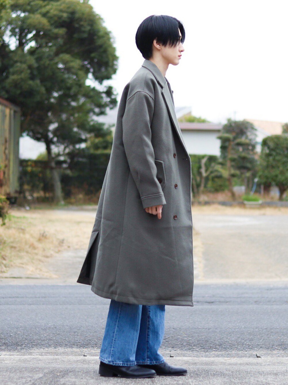 ホワイト系のニット/セーター、グレー系のチェスターコート、ブルー系のパンツを着用したメンズの冬コーディネートの2枚目の写真