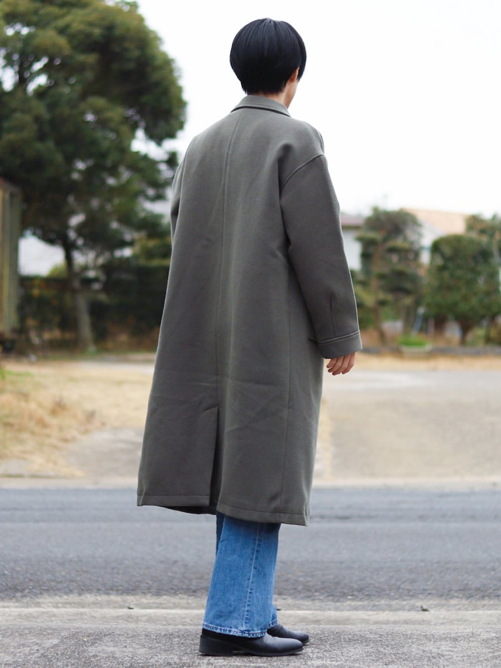 ホワイト系のニット/セーター、グレー系のチェスターコート、ブルー系のパンツを着用したメンズの冬コーディネートの3枚目の写真