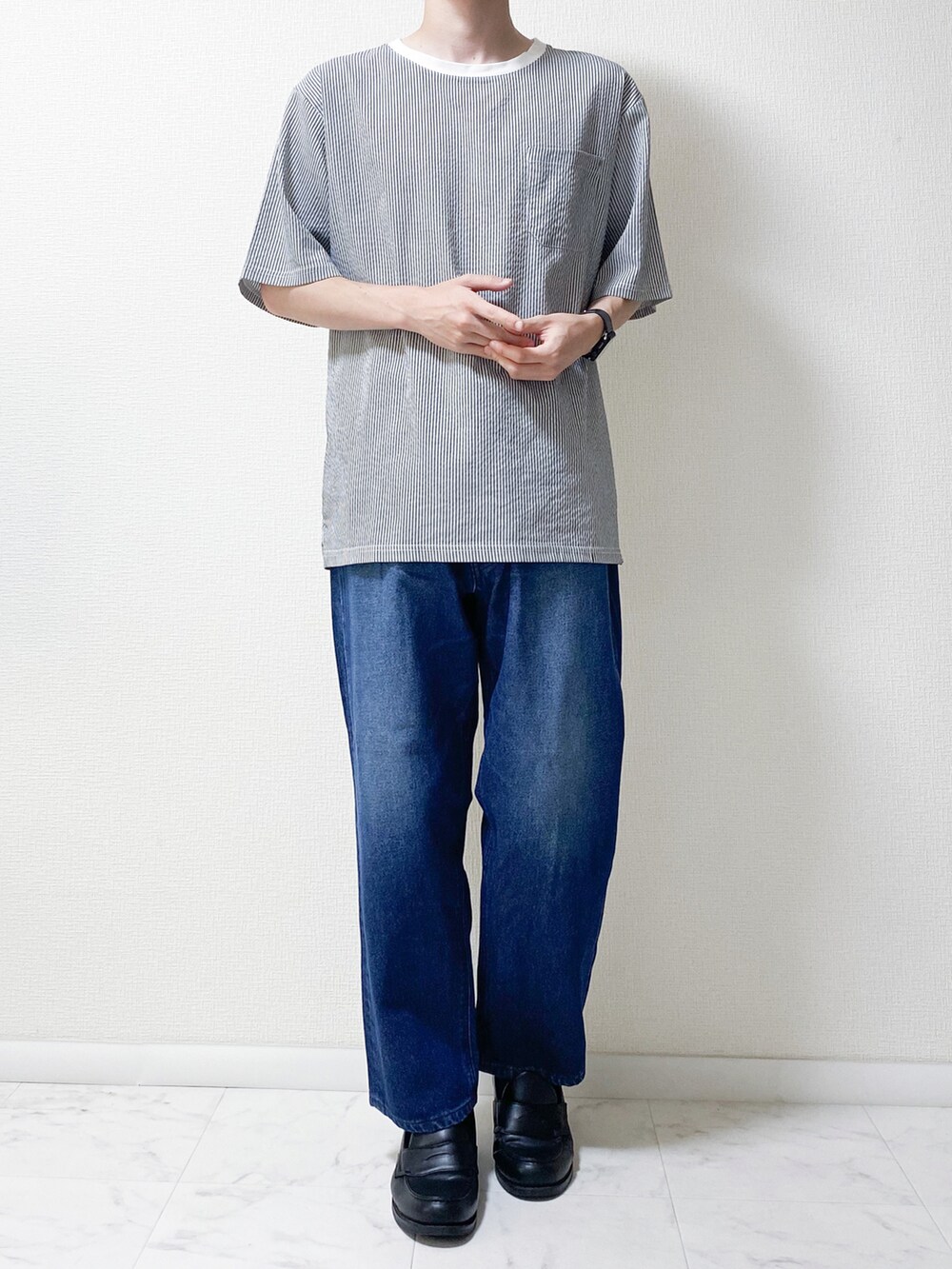 ブルー系のデニムパンツ、ブラック系のTシャツ/カットソー、ブラック系のローファーを着用したメンズの夏コーディネートの2枚目の写真