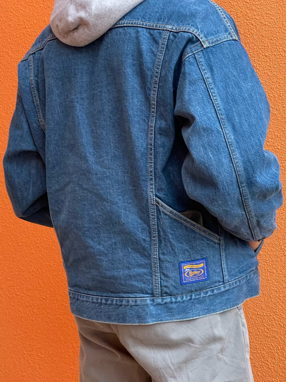 グレー系のパーカー、ブルー系のデニムジャケット、グレー系のチノパンツを着用したメンズの秋コーディネートの2枚目の写真