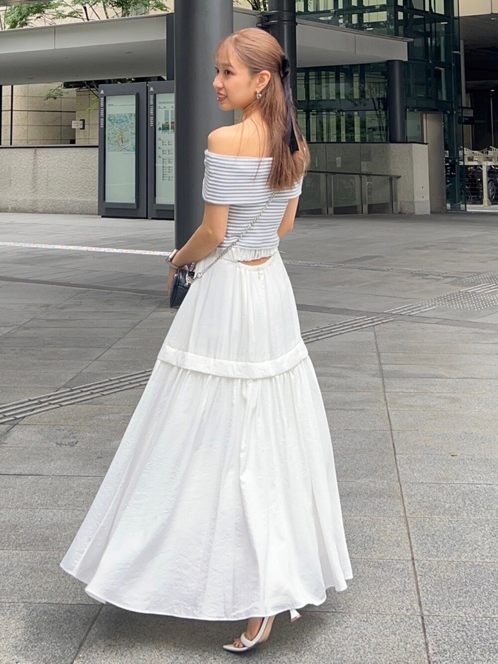 ホワイト系のスカート、ホワイト系のサンダル、ブラック系のTシャツ/カットソーを着用したレディースの夏コーディネートの2枚目の写真