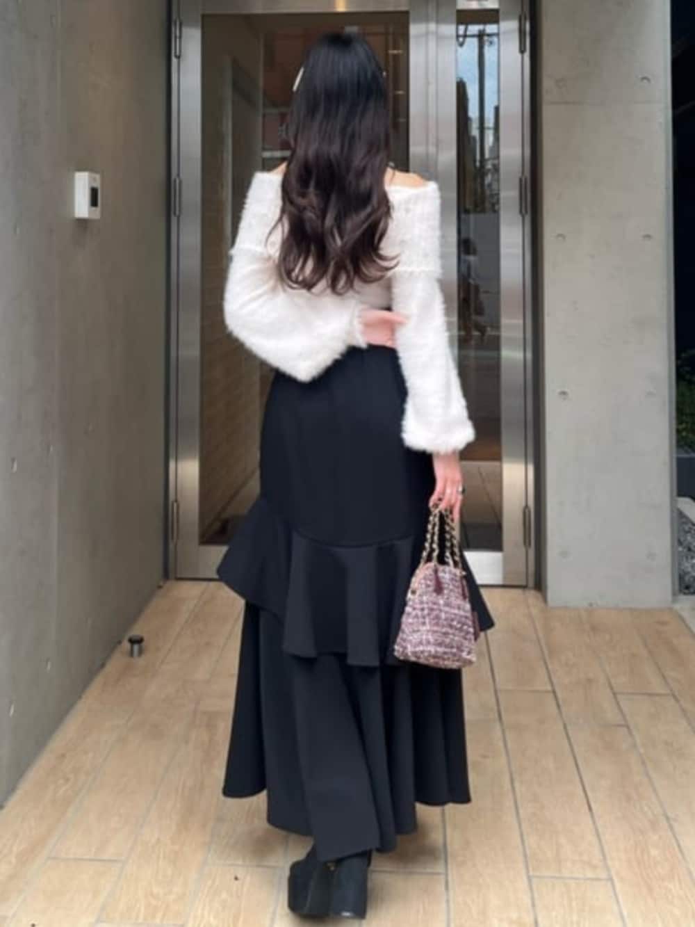 ブラック系のスカート、ブラック系のブーツ、レッド系のショルダーバッグを着用したレディースの秋コーディネートの2枚目の写真