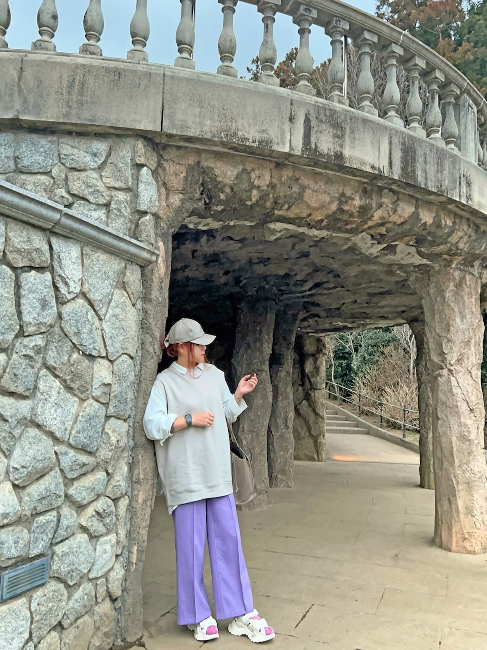 ホワイト系のサンダル、ベージュ系のバッグ、パープル系のパンツを着用したレディースの春コーディネートの2枚目の写真