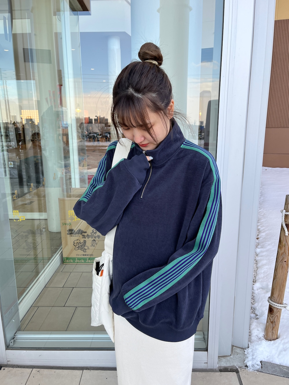 グリーン系のブルゾン、ホワイト系のスカート、ホワイト系のスニーカーを着用したレディースの冬コーディネートの2枚目の写真