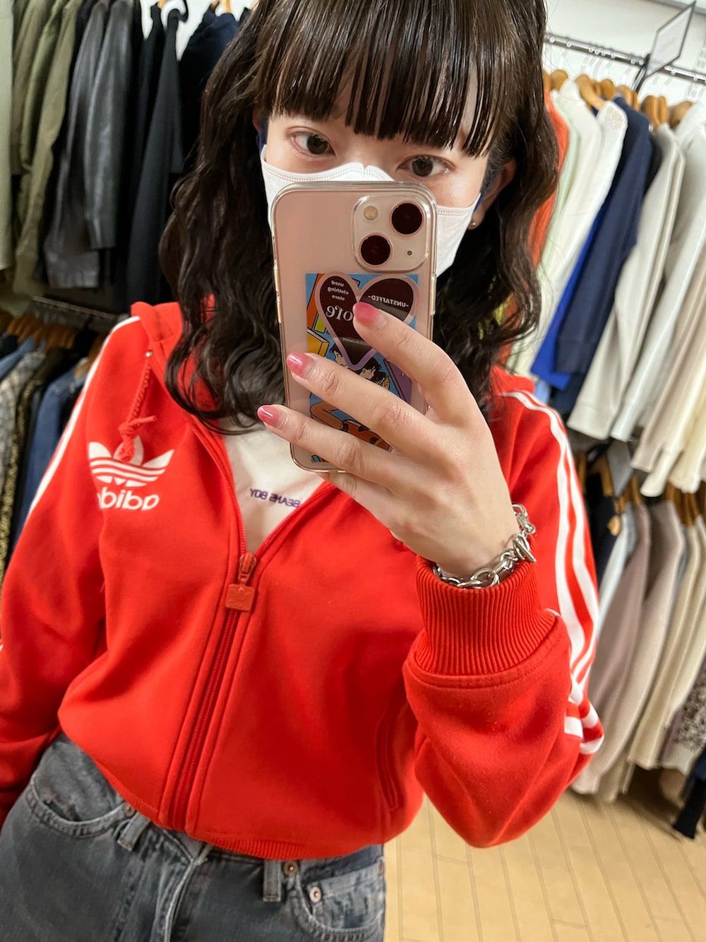 レッド系のパーカー、ブラック系のデニムパンツ、ベージュ系のTシャツ/カットソーを着用したレディースの春コーディネートの2枚目の写真