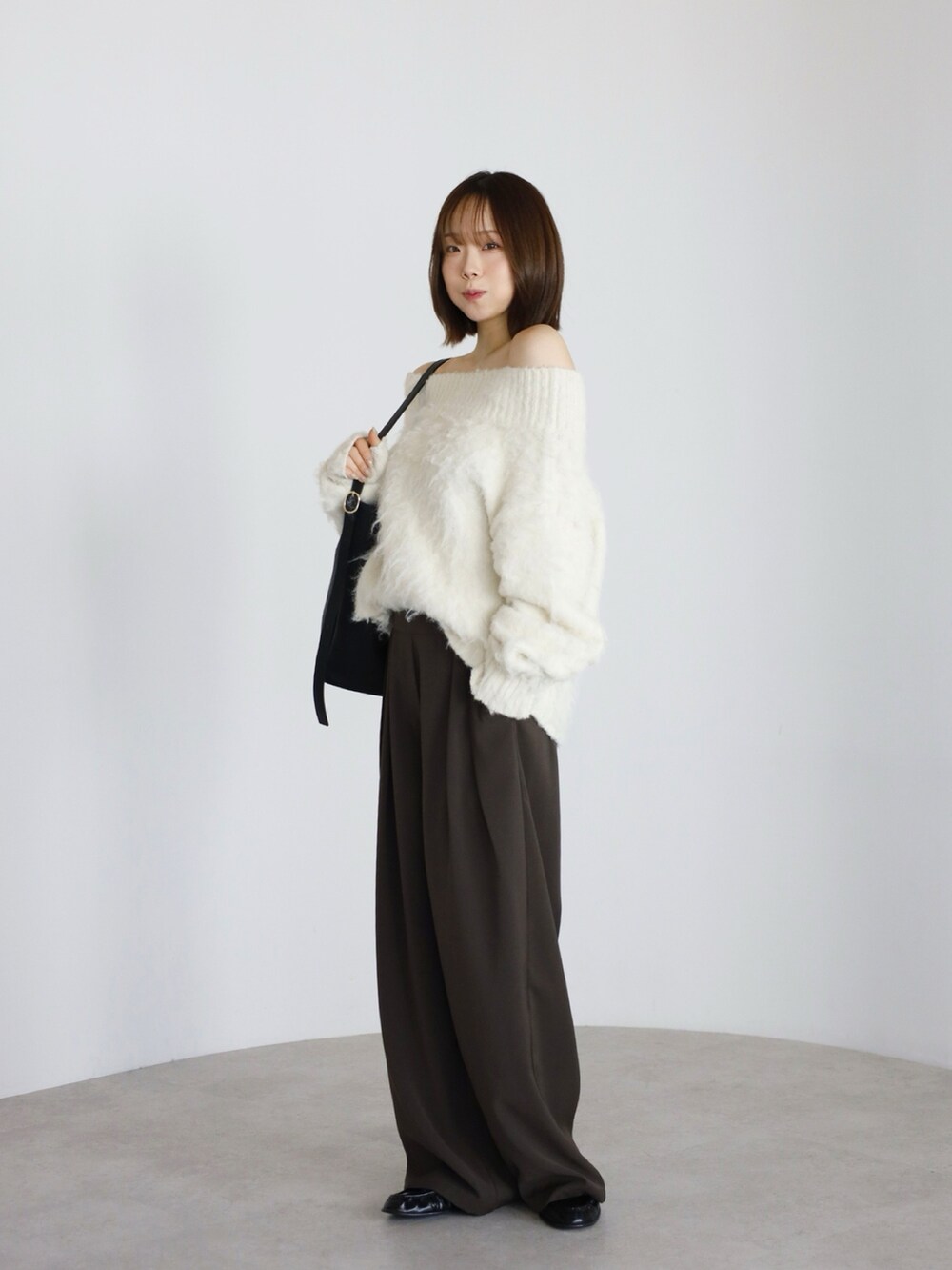 ブラウン系のその他パンツ、ホワイト系のニット/セーター、ブラック系のトートバッグを着用したレディースの冬コーディネートの2枚目の写真