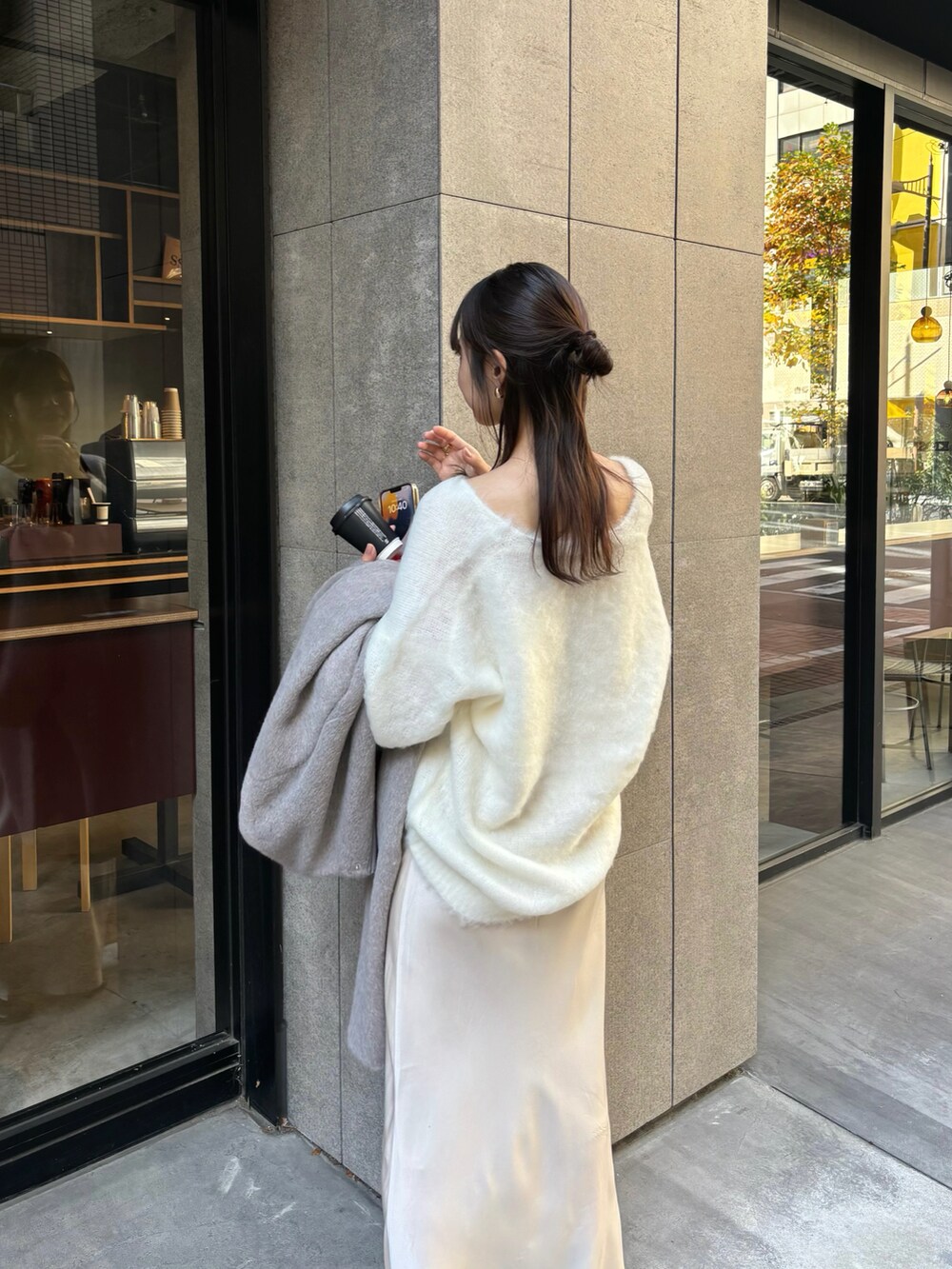 グレー系のノーカラーコート、ベージュ系のスカートを着用したレディースの冬コーディネートの3枚目の写真