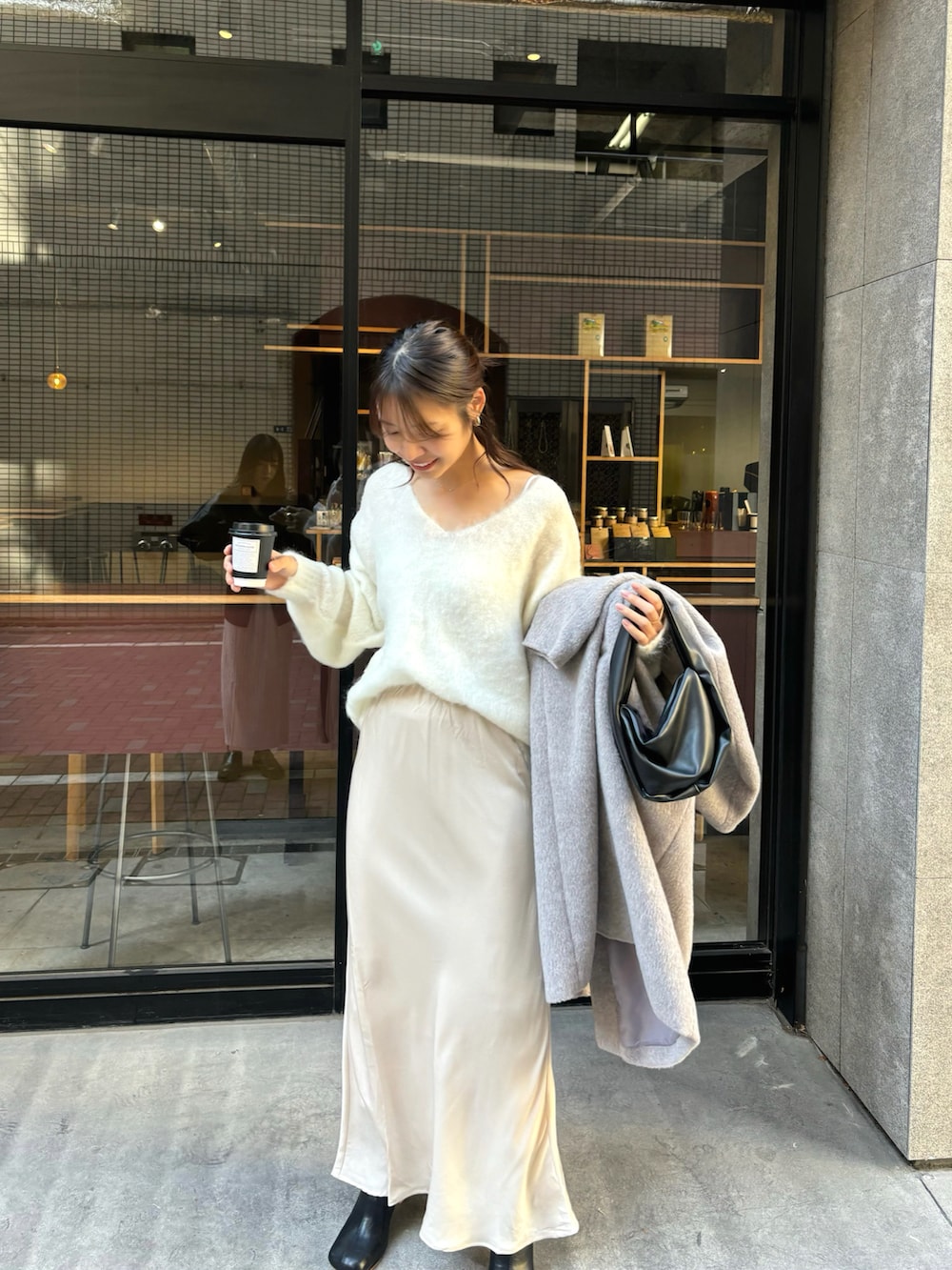 グレー系のノーカラーコート、ベージュ系のスカートを着用したレディースの冬コーディネートの4枚目の写真