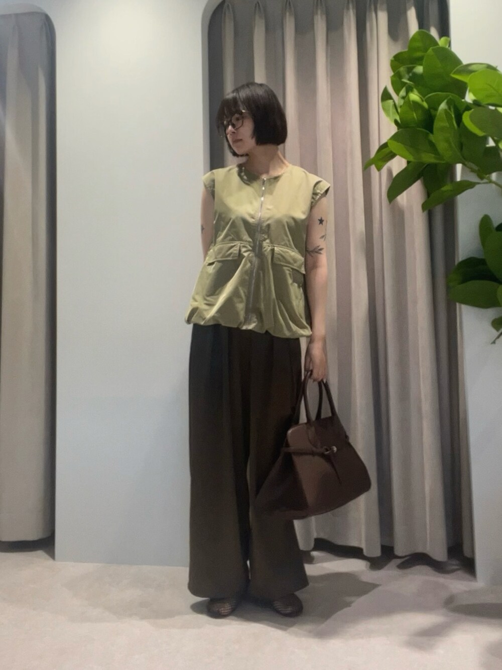 グリーン系のベスト、ブラウン系のその他パンツ、ブラウン系のハンドバッグを着用したレディースの夏コーディネートの2枚目の写真