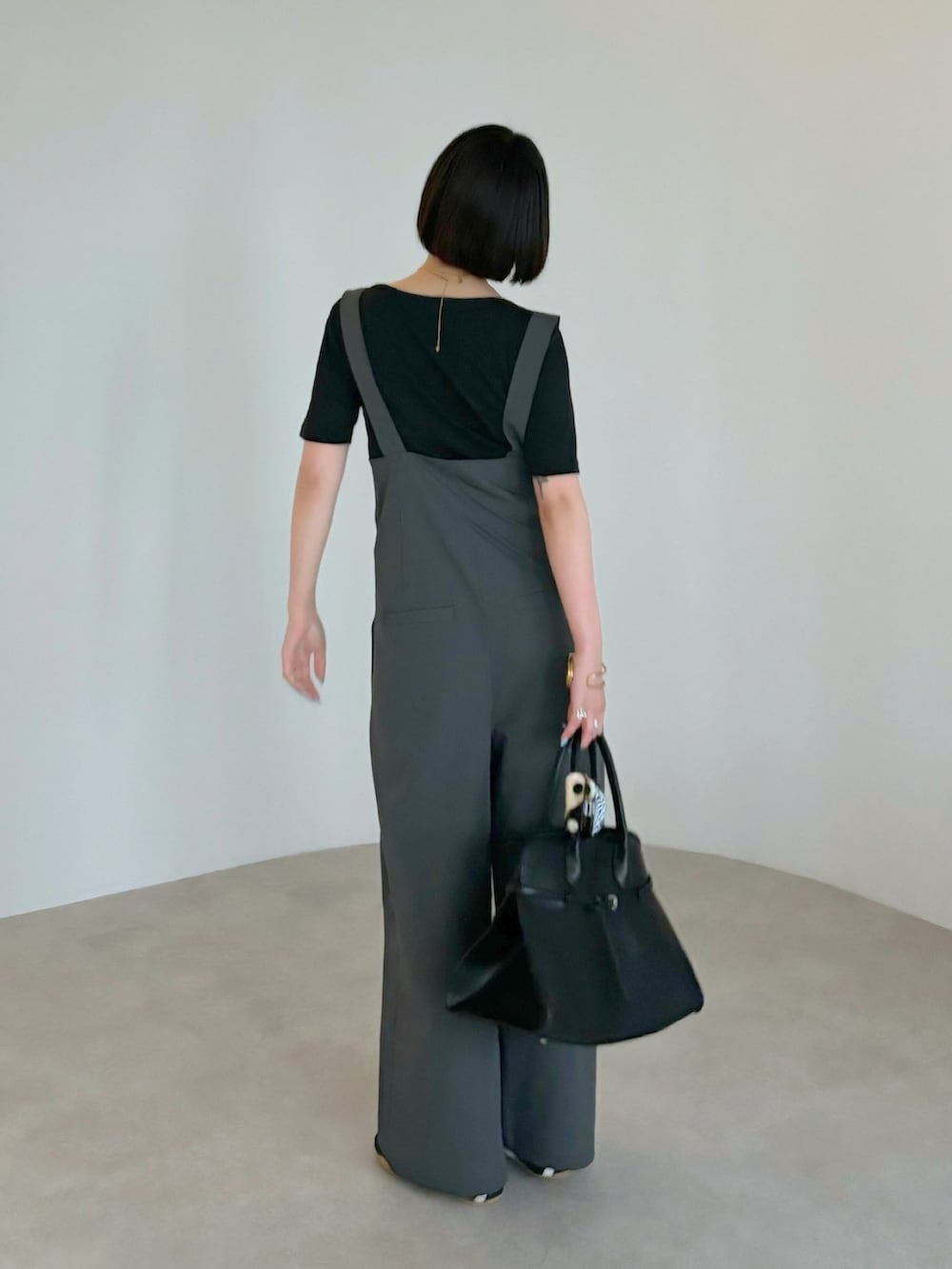 ブラウン系のハンドバッグ、ブラック系のTシャツ/カットソー、グレー系のサロペット/オーバーオールを着用したレディースの夏コーディネートの3枚目の写真