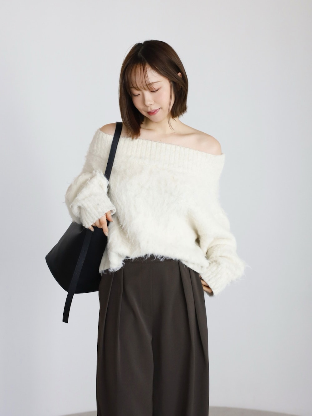 ブラウン系のその他パンツ、ホワイト系のニット/セーター、ブラック系のトートバッグを着用したレディースの冬コーディネートの3枚目の写真