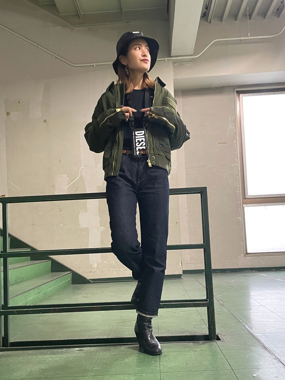 グリーン系のジャケット/アウター、ブルー系のデニムパンツ、ブラック系のハットを着用したレディースの秋コーディネートの2枚目の写真