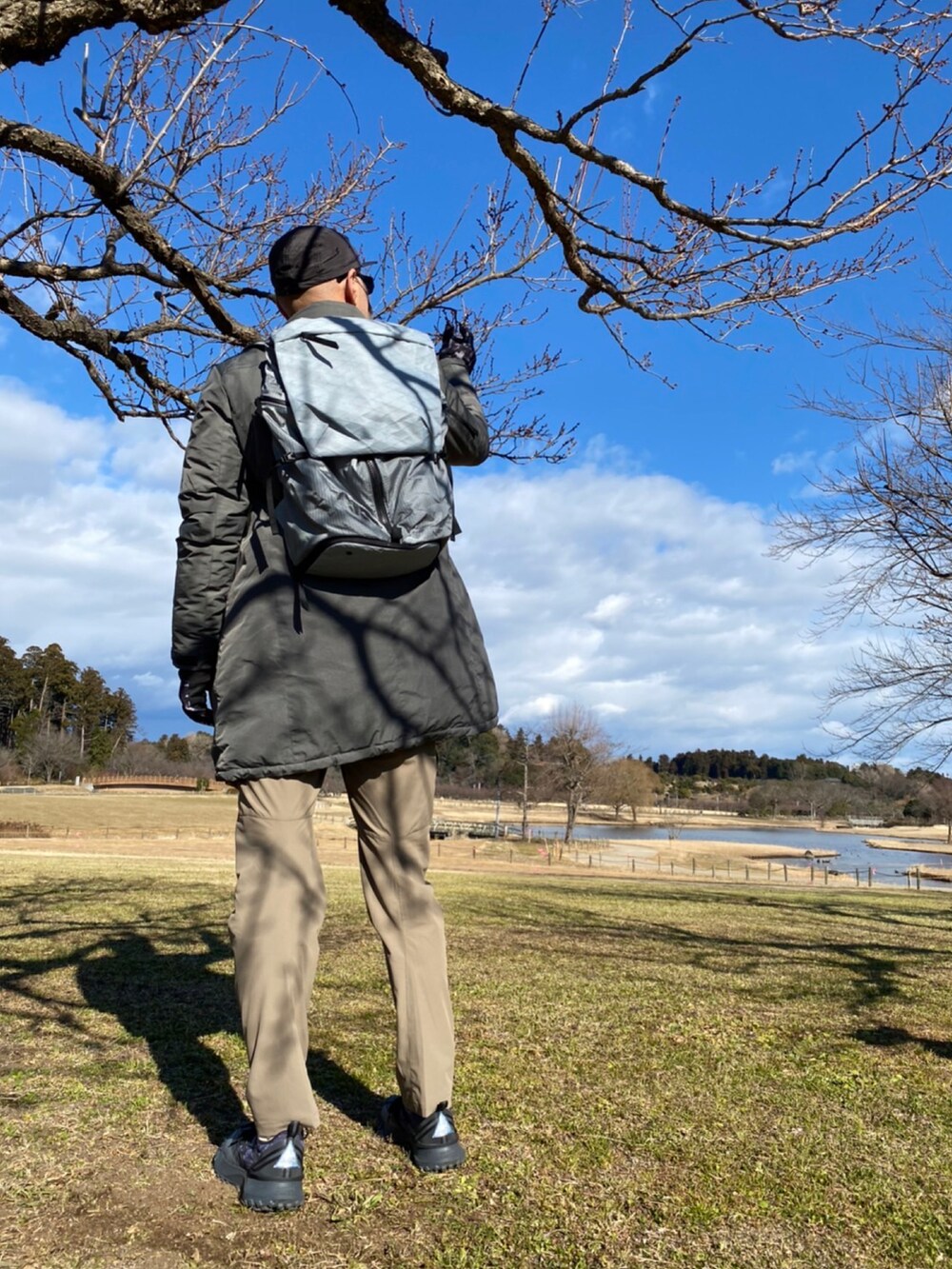 シルバー系のバックパック/リュック、グレー系のノーカラーコート、グレー系のスウェットを着用したメンズの冬コーディネートの2枚目の写真