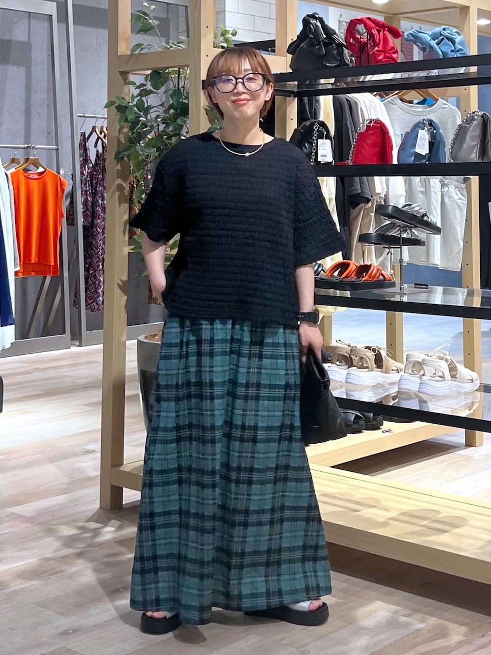 グリーン系のスカート、グレー系のサンダル、ブラック系のTシャツ/カットソーを着用したレディースの夏コーディネートの4枚目の写真