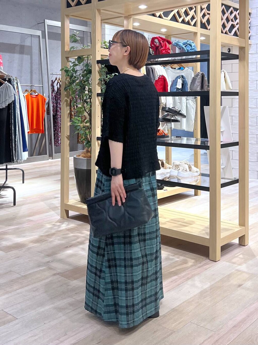 グリーン系のスカート、グレー系のサンダル、ブラック系のTシャツ/カットソーを着用したレディースの夏コーディネートの2枚目の写真