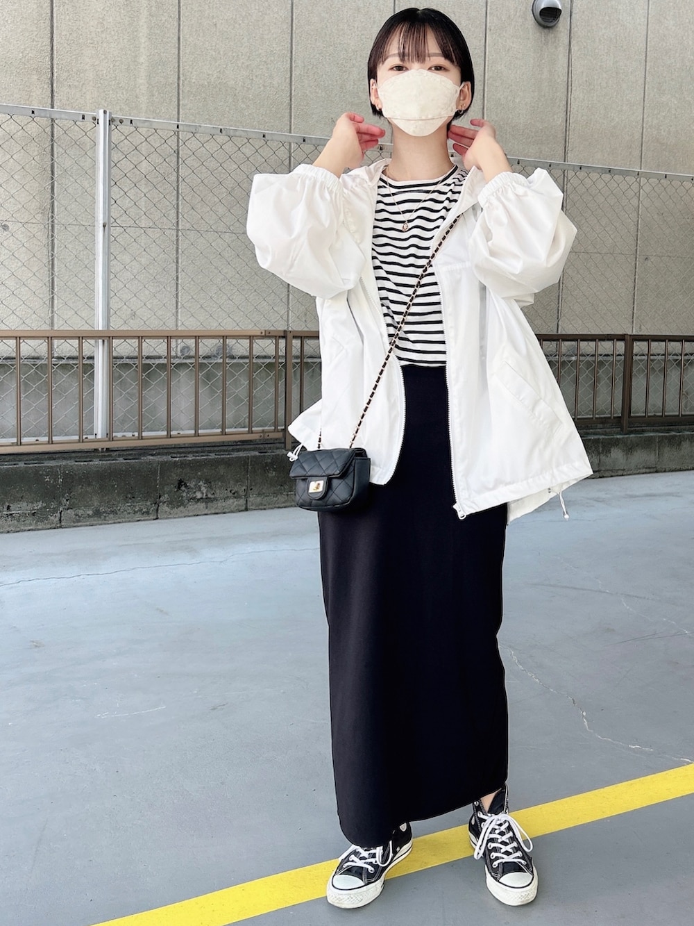 ホワイト系のマウンテンパーカー、ブラック系のショルダーバッグ、ブラック系のTシャツ/カットソーを着用したレディースの春コーディネートの2枚目の写真