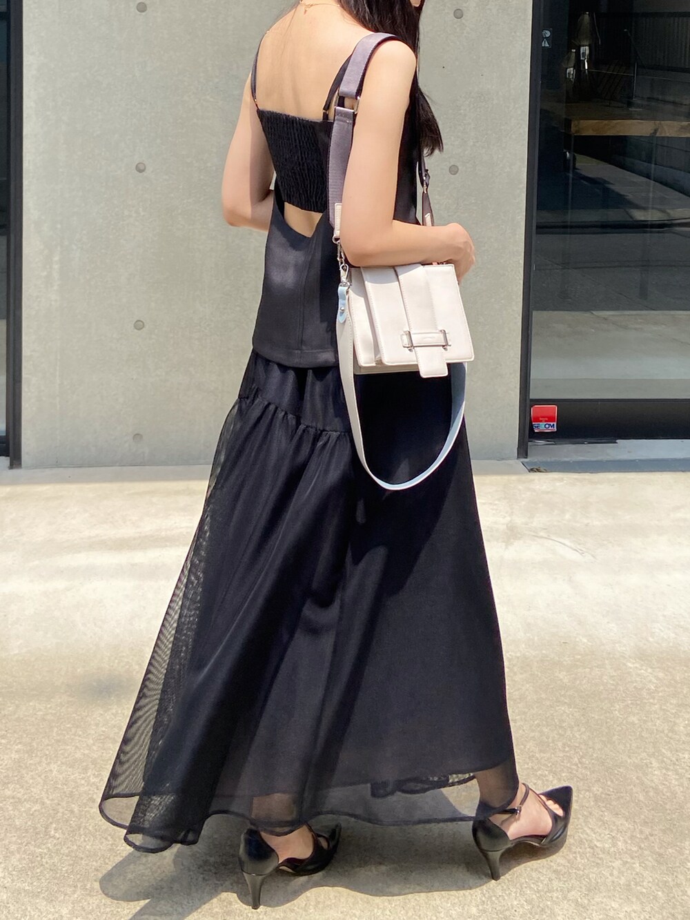 ブラック系のワンピース、ホワイト系のショルダーバッグを着用したレディースの夏コーディネートの2枚目の写真