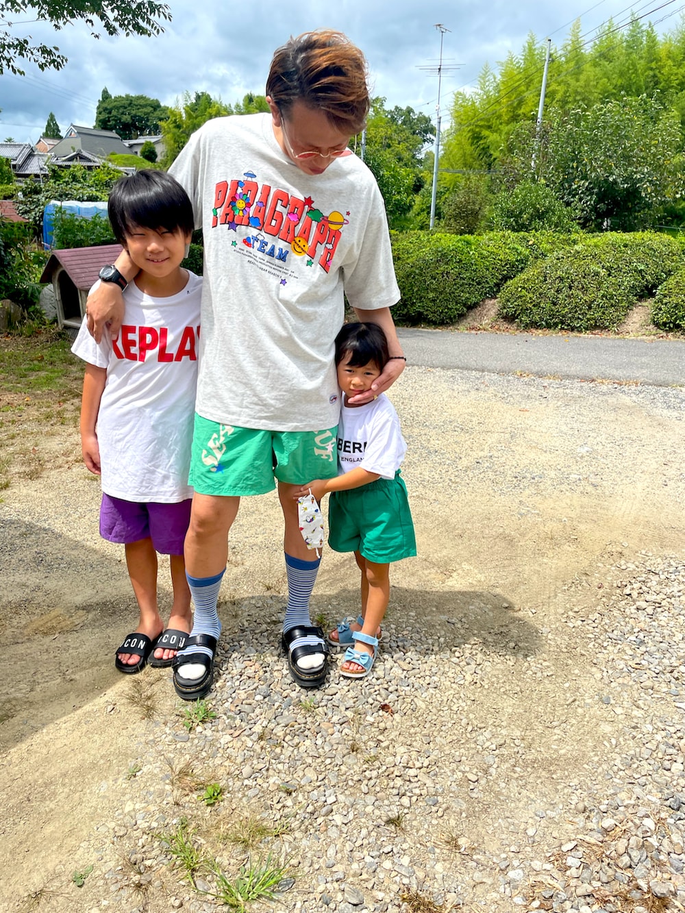 グレー系のTシャツ/カットソー、グリーン系のパンツ、ブラック系のサンダルを着用したメンズの夏コーディネートの2枚目の写真