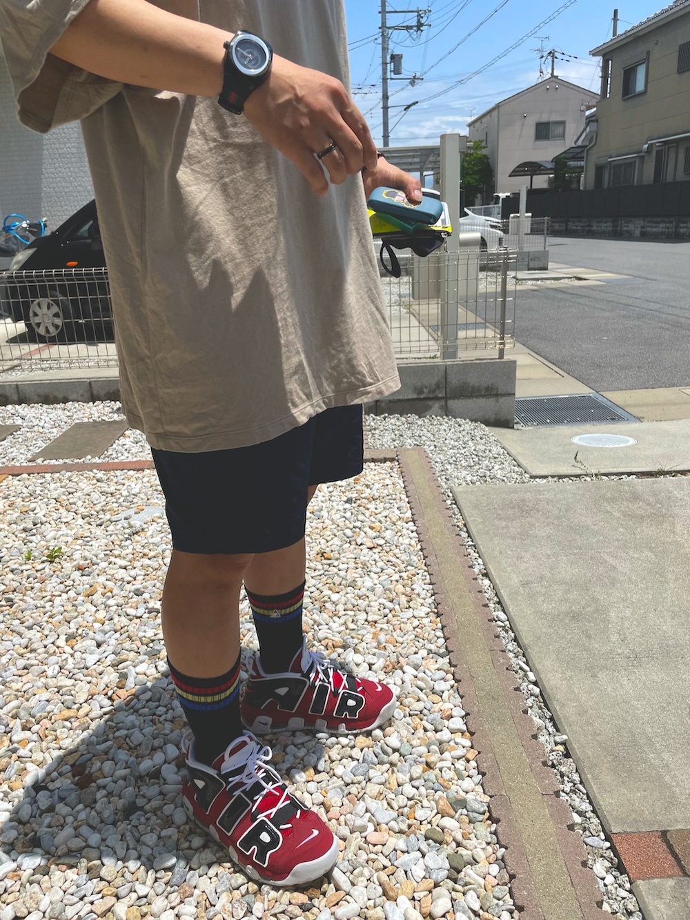 ベージュ系のTシャツ/カットソー、ブラック系のパンツ、レッド系のスニーカーを着用したメンズの夏コーディネートの3枚目の写真