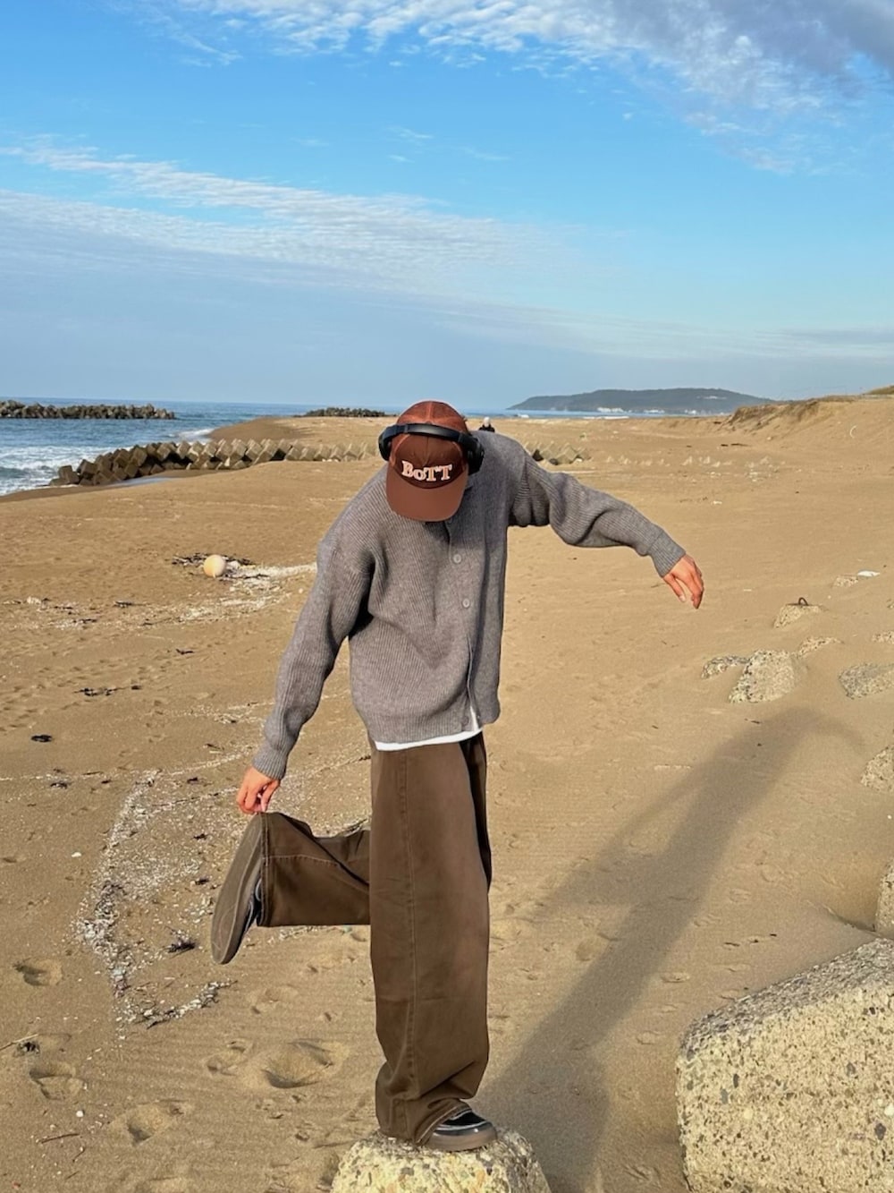 ブラック系のスニーカー、ブラウン系のキャップを着用したメンズの冬コーディネートの2枚目の写真